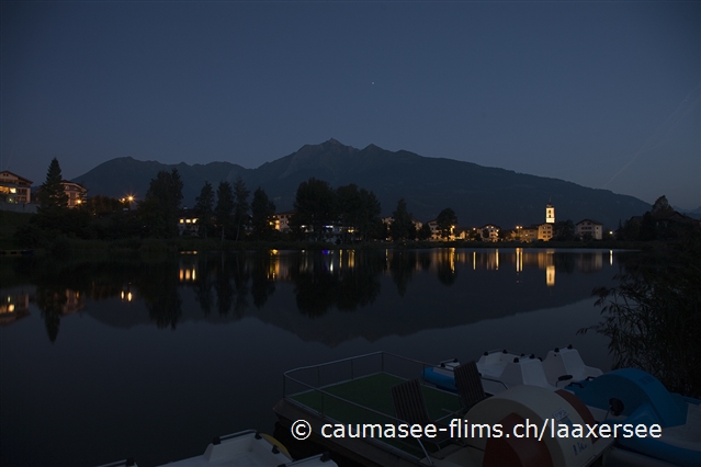 Blick ber den Laaxersee bei Nacht. Im Vordergrund Pedalo-Boote, im Hintergrund Laax-Dorf.